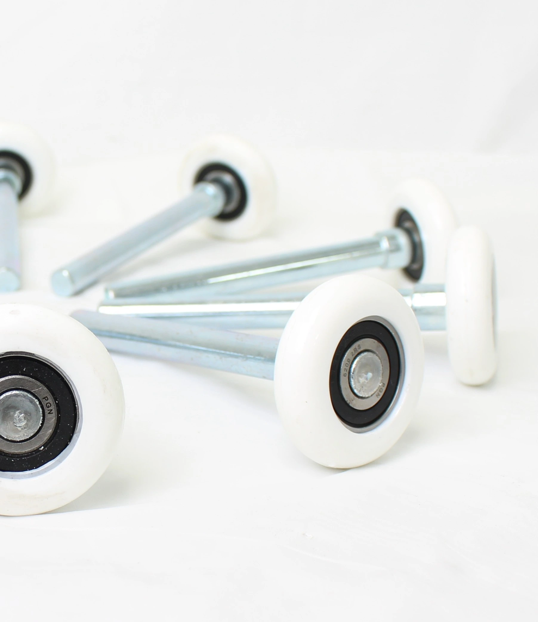 White plastic roller wheels with metal bearings and attached steel stems.