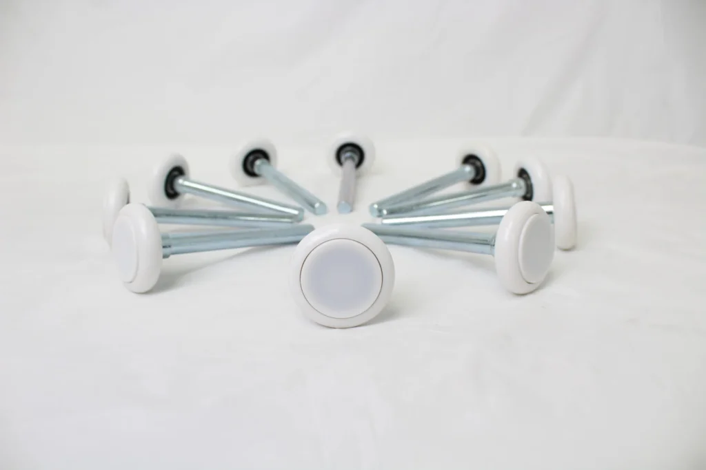 Set of white nylon rollers with metal shafts arranged in a circle.