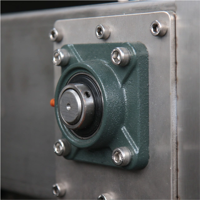 Close-up of a four-bolt flange bearing unit mounted on a stainless steel surface in industrial machinery