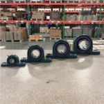 Row of PGN pillow block bearings in different sizes placed on a table inside a warehouse with shelves in the background