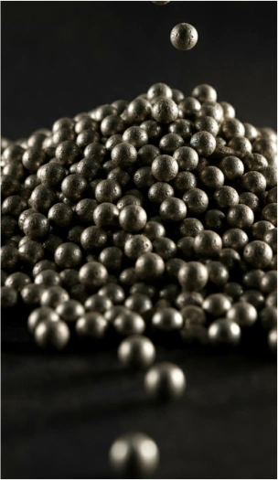 Steel grinding media balls piled together with one ball falling above the heap.