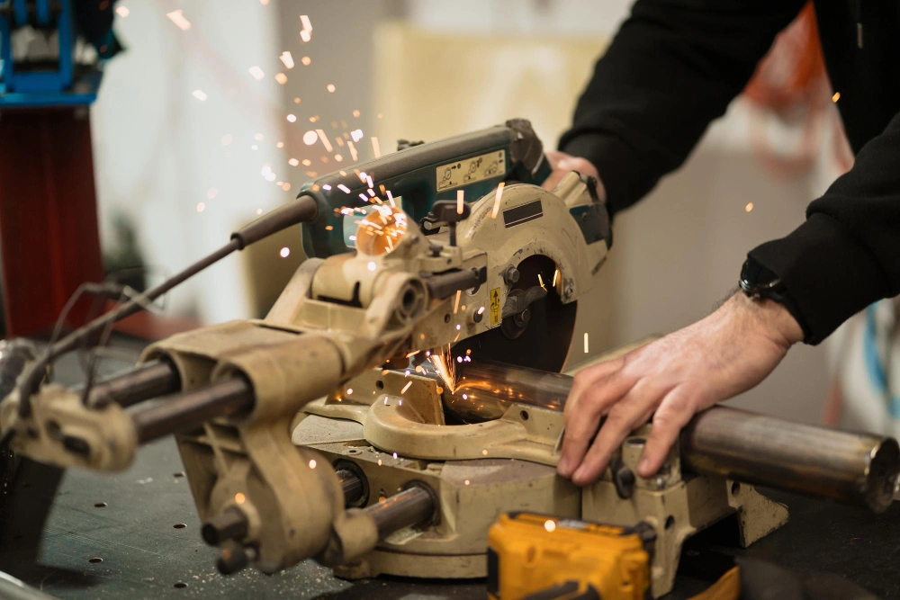 Worker using a metal cutting saw with sparks flying during operation.