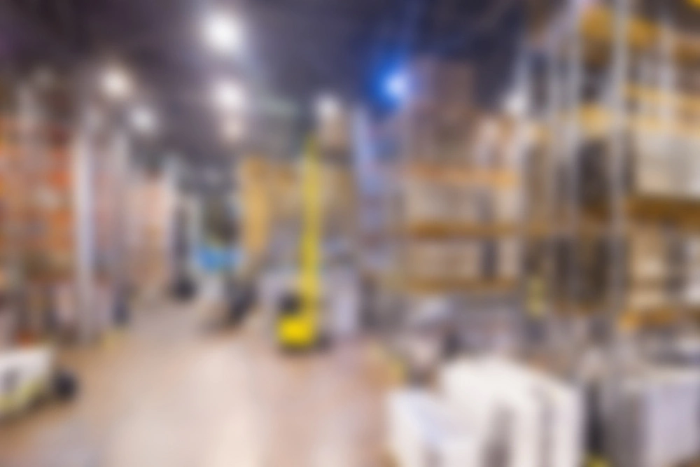 Blurred view of a large warehouse with shelves and industrial equipment.